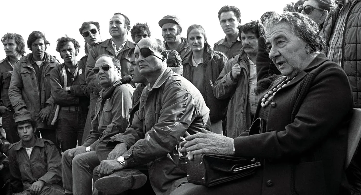 Prime Minister Golda Meir, accompanied by Defense Minister Moshe Dayan, meets with Israeli soldiers at a base on the Golan Heights during the 1973 Yom Kippur War.